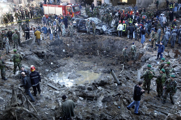 Rescue workers and soldiers stand around a massive crater after a bomb attack that tore through the motorcade carrying Prime Minister Rafik Hariri in Beirut, Lebanon in 2005.