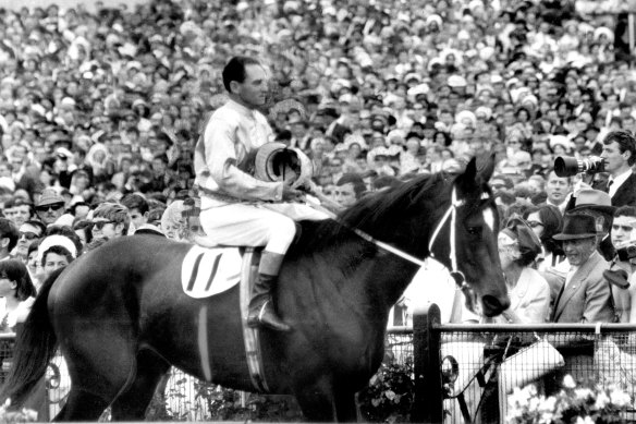 Elated jockey Jim Johnson and runaway Melbourne Cup winner Rain Lover return to scale in 1968.