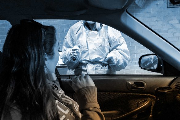 At a drive-through testing centre, a nurse prepares to swab reporter Sherryn Groch for COVID-19.