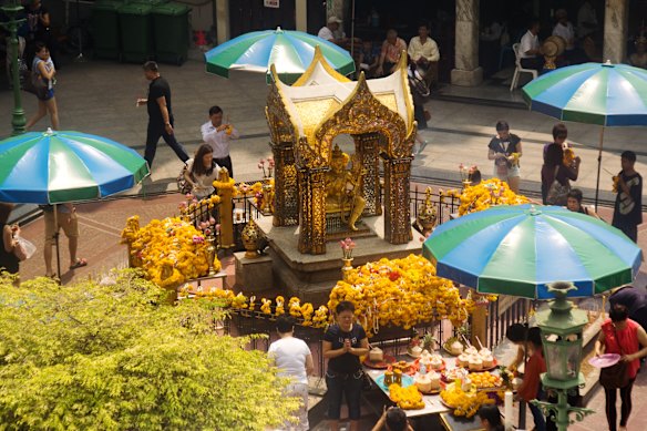 Visitors pray and leave offerings at Erawan Shrine.