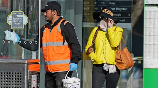 A member of the COVID-19 Cleansing Team wipes a window at a tram stop across the road from the Rydges on Swanston hotel in Melbourne.