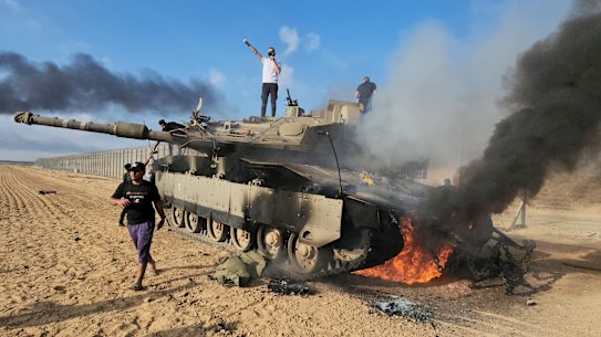 Palestinos em um tanque israelense destruído na cerca da Faixa de Gaza, a leste de Khan Younis.