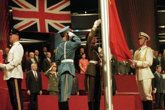 Birleşik Çin Silahlı Kuvvetleri renk muhafızlarının üyeleri, eski İngiliz kolonisinin Pekin'e teslim edildiği anı işaret ederek, 30 Haziran 1997'de Hong Kong'da Çin bayrağını yükseltti.  Prens Charles sağ alt köşede.