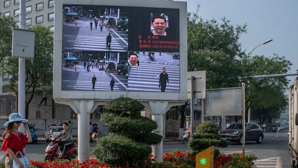 A road in Xiangyang, China equipped with facial recognition technology, displays photos of jaywalkers alongside their name and identification number.