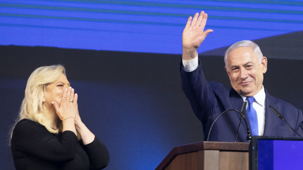 Israel's Prime Minister Benjamin Netanyahu waves with wife Sara at the Likud party HQ in Tel Aviv early on Wednesday morning.
