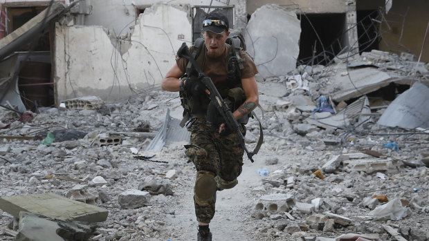 A US-backed Syrian Democratic Forces fighter runs in front of a damaged building as he crosses a street on the front line, in Raqqa, Syria, last year. 