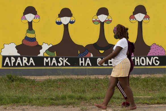 A South African woman walks past a coronavirus-themed mural promoting the use of face masks in public.