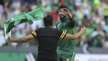 A fan runs onto the field to congratulate Imad Wasim.