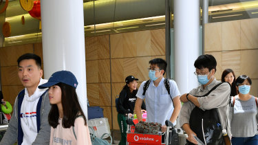 Passengers wearing protective masks arrive at Sydney International Airport.
