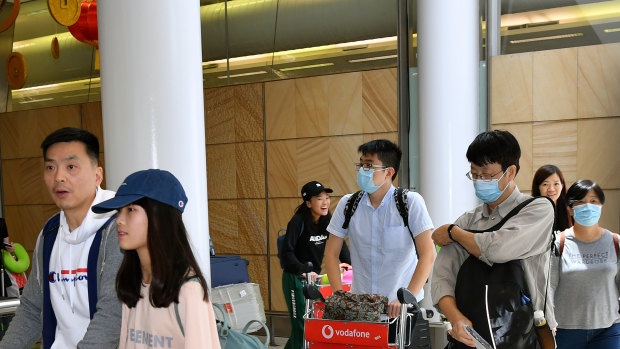 Passengers wearing protective masks arrive at Sydney International Airport.