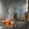Rebel fighters stand next to the burning grave site of Syria’s late president Hafez al-Assad at his mausoleum in the family’s ancestral village of Qardaha in the western Latakia province.
