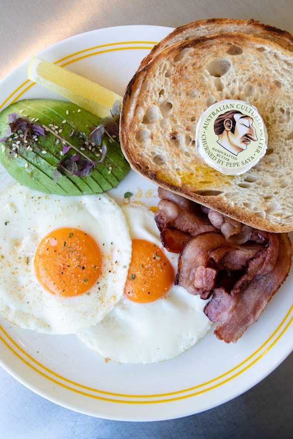 Fried eggs and toast with avocado and bacon.