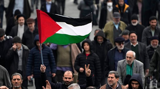 A man holds up a Palestinian flag.