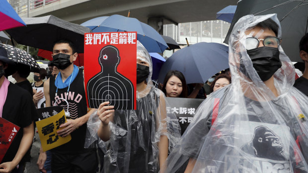 Protesters, some wearing eye patches to show solidarity to a woman reportedly injured in the eye by a beanbag fired by police, hold up a banner that reads 'We are not targets'. 