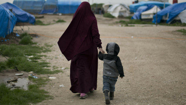 A woman walks with her son at Camp Roj in north Syria. 