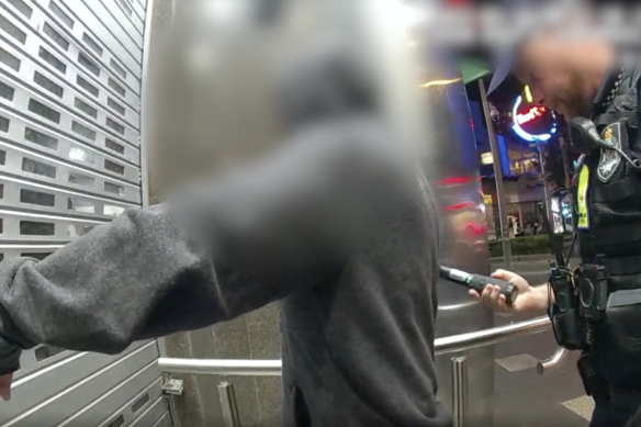 Queensland police officers search a person with a metal detection wand during the trial in Gold Coast party precincts. 