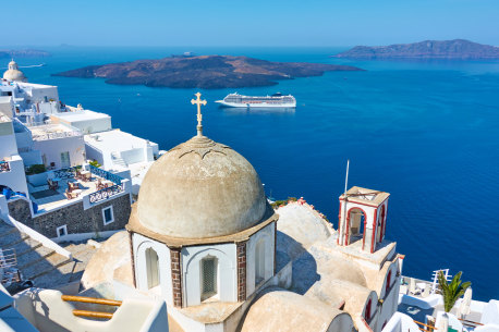 Fira town in Santorini island in Greece with cruise ship in the background.