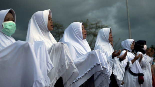 Indonesian women attend a prayer for the victims of the September 28 earthquake and tsunami on Talise Beach in Palu, Central Sulawesi, Indonesia, on Friday.