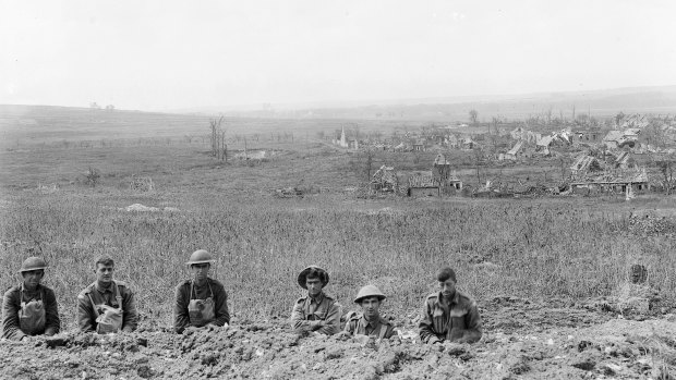 Australian and American troops in a trench after the Battle of Hamel with the village, then freed of Germans, behind them.