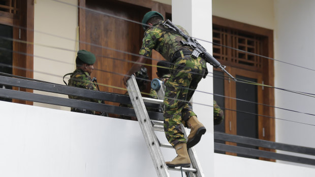 A Sri Lankan police commando enters a house suspected to be a hideout of militants following a shoot out in Colombo, Sri Lanka on Sunday.