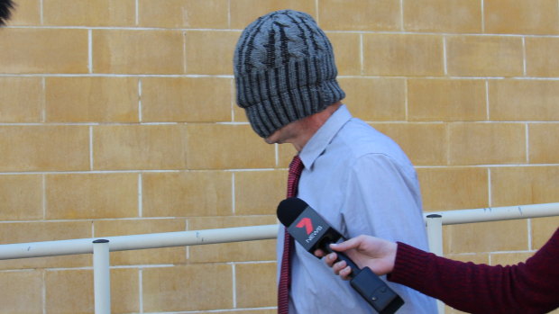 Simon Squires leaves Burwood Local Court with a beanie over his face.