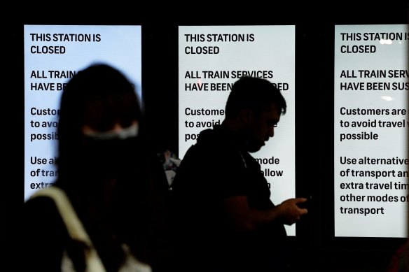 Commuters at the entrance to Central Station stand in front of notices stating the station is closed and all train services have been suspended.