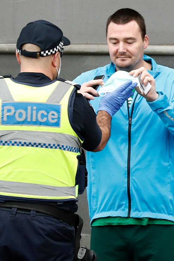 A man is confronted by a police officer at the anti-lockdown protest.