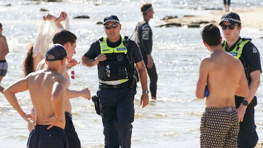 Police officers inform beachgoers that the beach is closed at Brighton Beach.