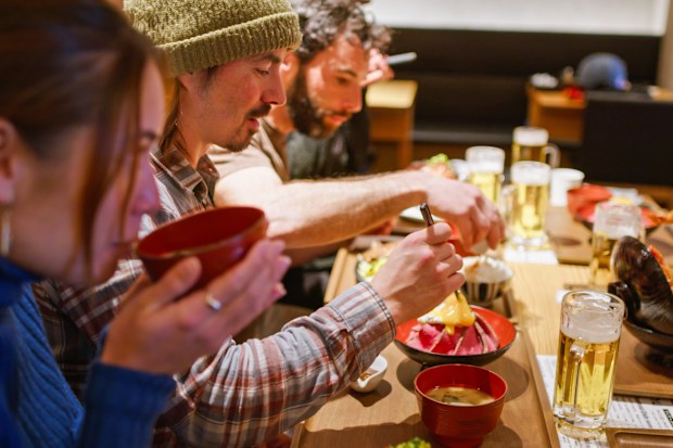 Three friends having a meal with their friends after a skiing session in Niseko, Japan.