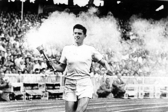 Ron Clarke carries the flame around the arena during the opening ceremony at the Melbourne 1956 Olympics.