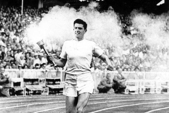 Ron Clarke carries the flame around the arena during the opening ceremony at the Melbourne 1956 Olympics.