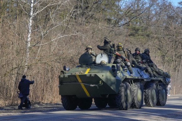A man pushes a baby stroller as he waves to Ukrainian soldiers on an armoured personnel carrier passing by in the Vyshgorod region close to Kyiv this month. 