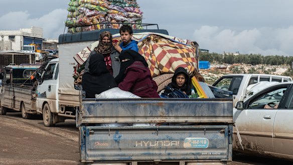 Displaced Syrian families ride in the back of a truck loaded with families' possessions in Idlib, Syria. 