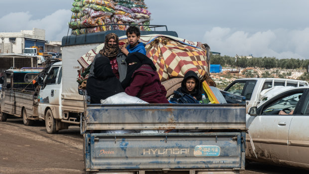 Displaced Syrian families ride in the back of a truck loaded with families' possessions in Idlib, Syria. 