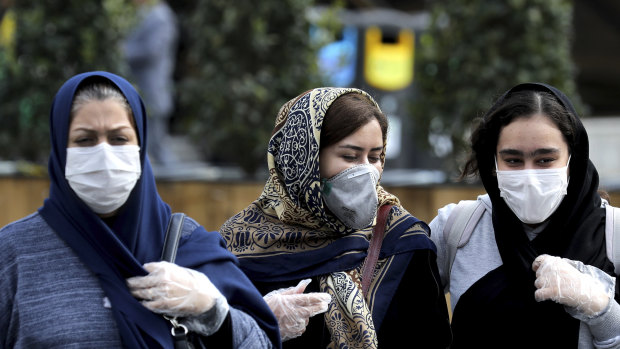 People wear masks to help guard against the Coronavirus on a street in downtown Tehran, Iran.