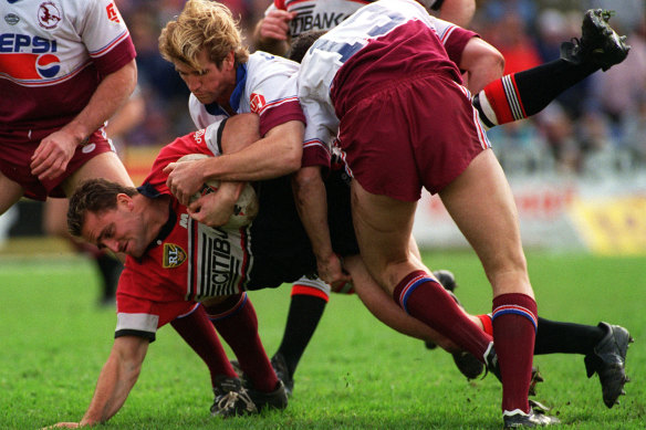 North Sydney enforcer Billy Moore is driven into the Brookvale turf by Manly’s Des Hasler in 1995.