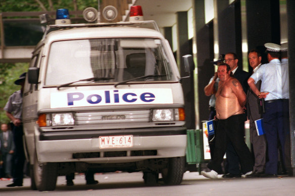 Police escort a man that had a fake bomb strapped to himself in the National Mutual Building in Collins Street.