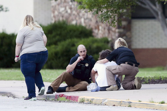 Tulsa Police talk to a young man at Memorial High School as he waits to be reunited with a family member who was evacuated from the scene of a shooting at the Natalie Medical Building in Tulsa.