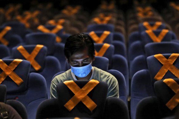 A man checks his mobile phone as he sits amid physical distancing markers prior to the start of a movie at the recently reopened CGV Cinemas theatre in Jakarta, Indonesia, last month. 