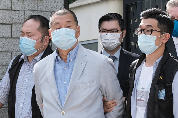 Jimmy Lai, second left, is led away from his residence by law enforcement officials in Hong Kong on Monday. 