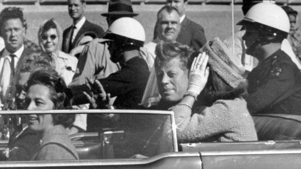 President John F. Kennedy, with wife Jacqueline, waves from his motorcade in Dallas soon before his assassination on November 22, 1963. 