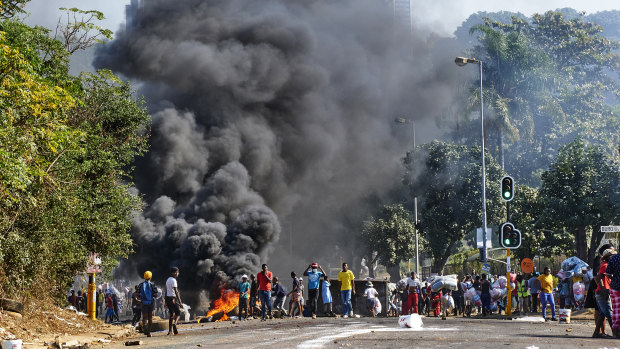 Looters outside a shopping centre alongside a burning barricade in Durban, South Africa.