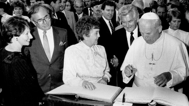 Pope John Paul II signs the visitors' book at Parliament House as Joan Child, Bob Hawke and John and Janette Howard look on. November 24, 1986