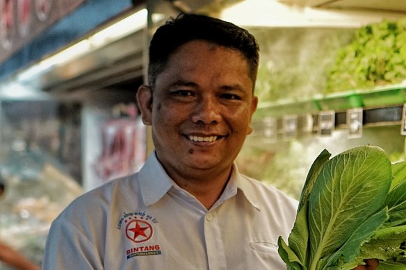 Bintang supermarket manager Kastrianto poses with fresh produce wrapped in banana leaves, not plastic.