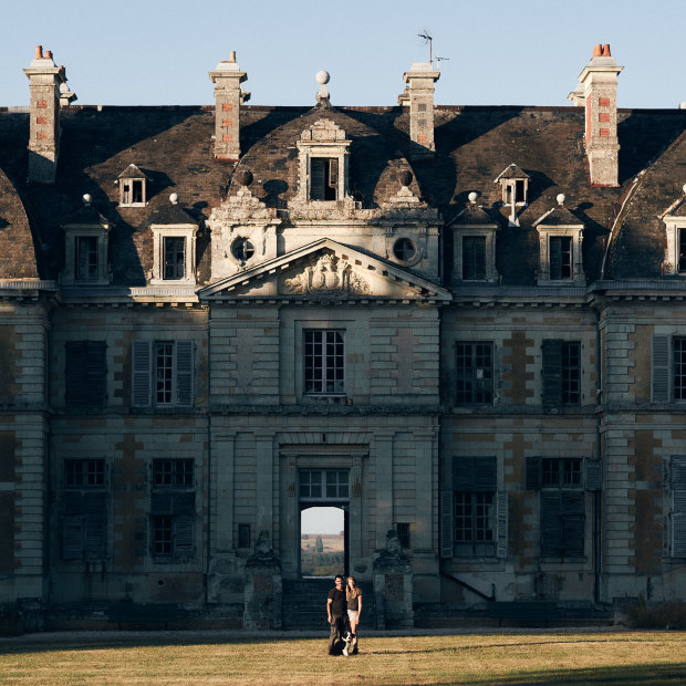 Tim Holding with his fiancée, Felicity Selkirk, and dog Truffe outside their 105-room 
fixer-upper.