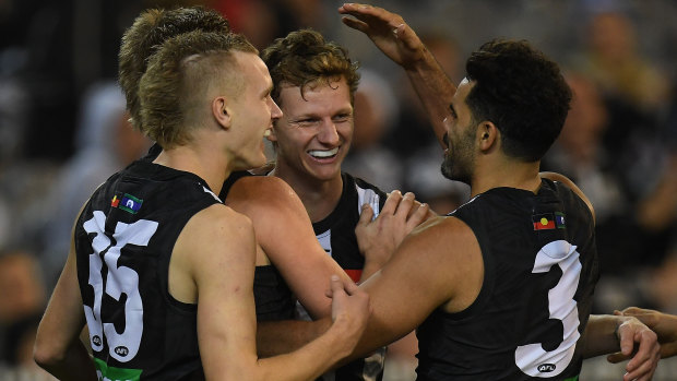 Six-shooter: Will Hoskin-Elliot of the Magpies (third from left) is congratulated after adding another major.
