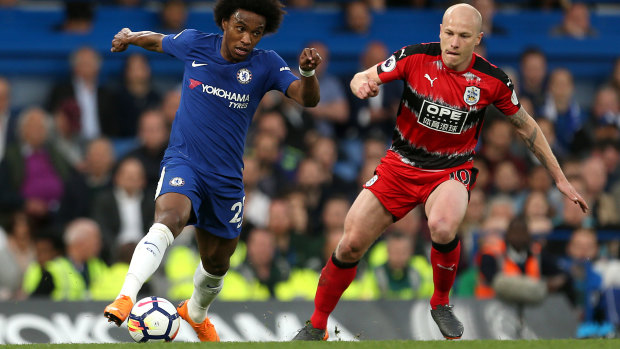Staying up: Aaron Mooy challenges Willian for the ball.