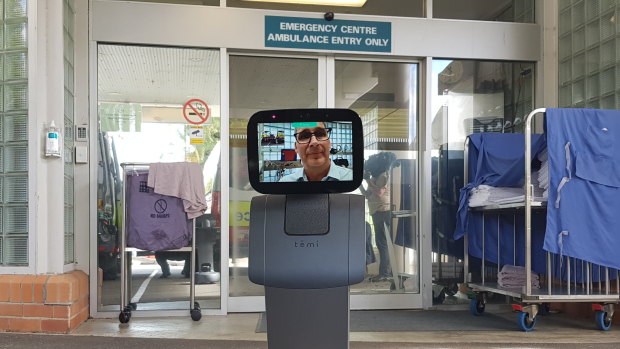 Dr Mark Baldwin uses a Temi telepresence robot outside Greenslopes hospital's emergency room.