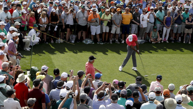 Tigermania: Tiger Woods hits his tee shot in front of a huge crowd during practice.