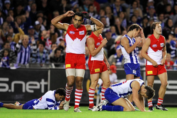 Swans and Kangaroos players exhausted as the final siren signals a draw.
